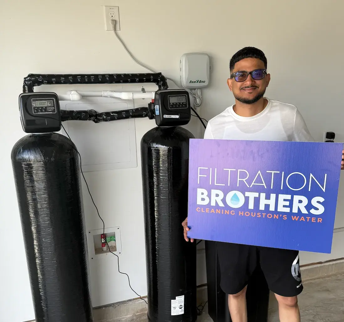 Filtration Brothers team member holding sign next to whole-home water system